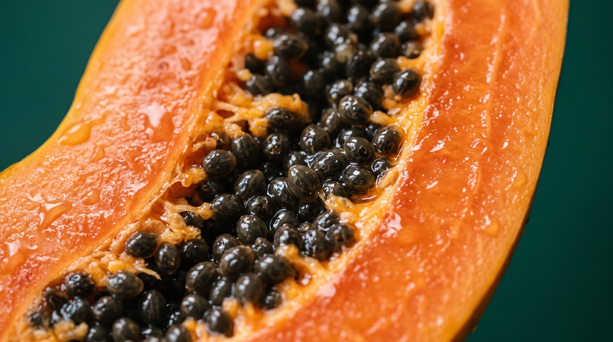 Macro detail of papaya flesh on a deep green background